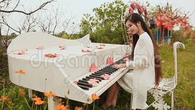 越南女孩留着长长的黑发在户外<strong>弹钢琴</strong>。 秋天的主题。 枫叶散落在钥匙上。